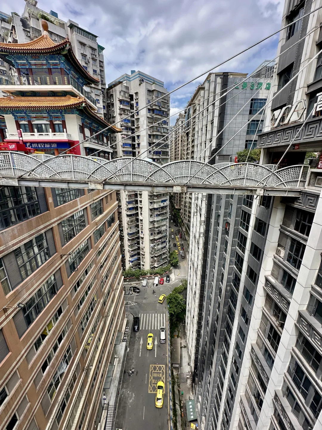 High-altitude pedestrian suspension bridge connecting multi-story residential buildings high above street level in Chongqing.